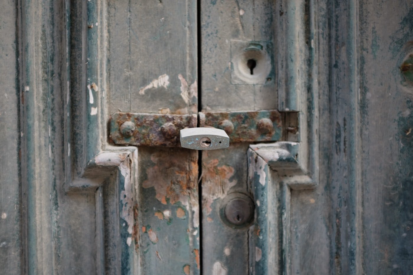 Padlock securing a rusted latch on a weathered door